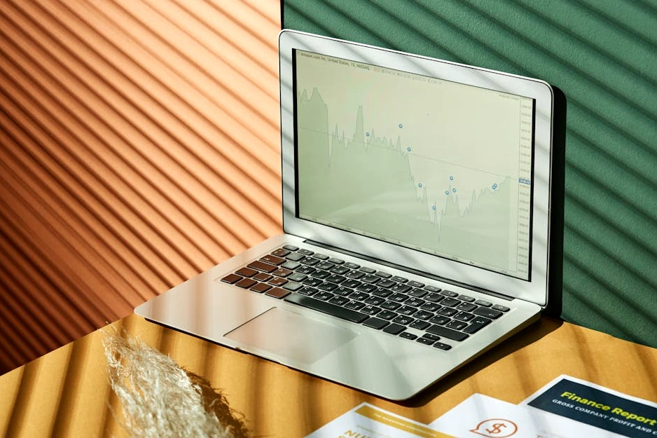 Analityk pracujący nad wykresem danych rynkowych na laptopie.